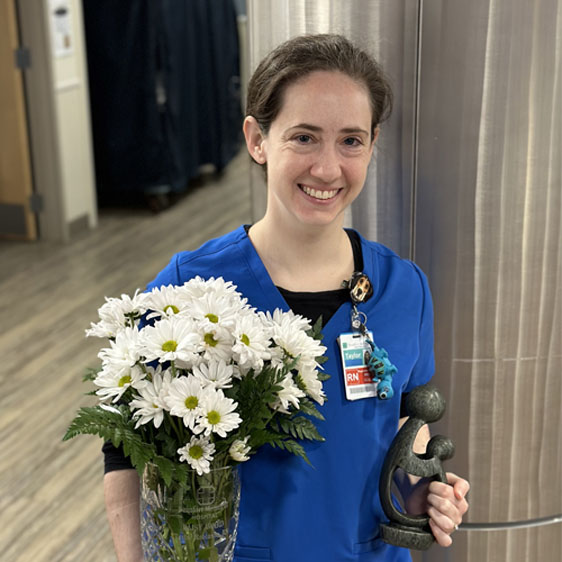 Taylor Robinson, RN, poses with a bouquet of daisies