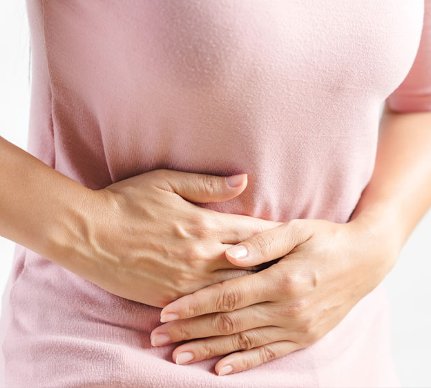 A woman in a pink shirt holds her stomach with her hands