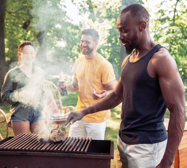 A person grilling outdoors with friends