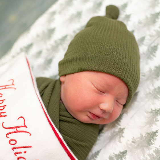 An infant in sage green clothing