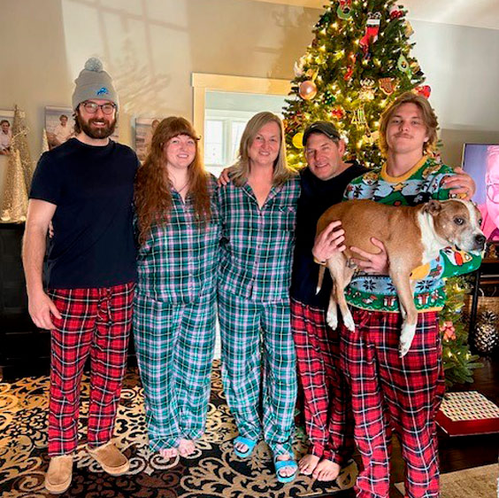 Dr. John Krcmarik, his wife, and three children wearing flannel in front of a Christmas tree inside of a home