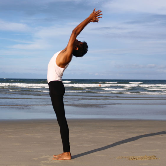 man doing yoga on the beach