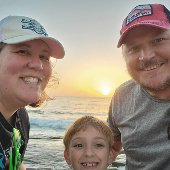 The Newman family smile at the camera while at the beach.