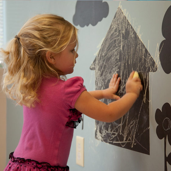 A little girl draws on a chalkboard wall in Beaufort Memorial's pediatric occupational therapy center