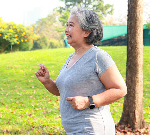 Older woman walking briskly with a grassy area in the background