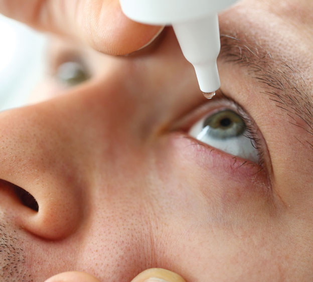 A close-up image of a man putting drops in his eye