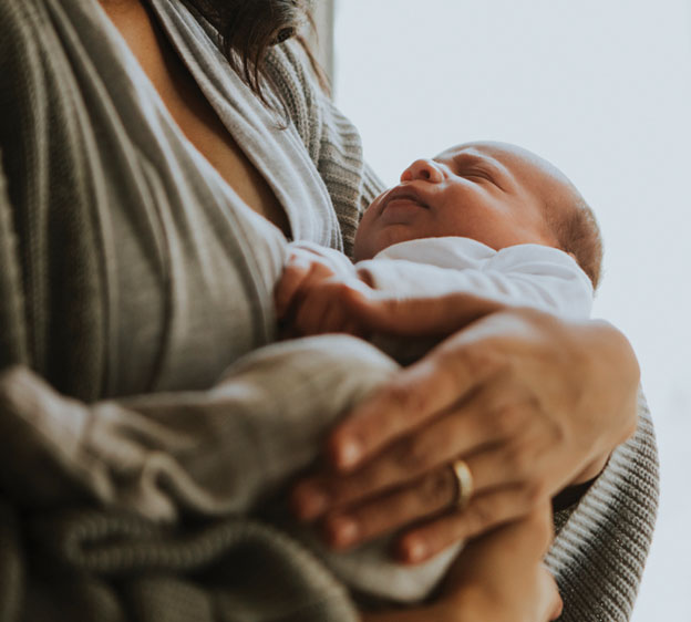 A small infant being held in someone&rsquo;s arms