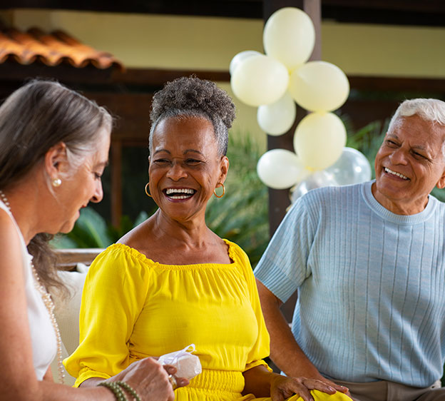 A group of three people smiling and looking at each other.