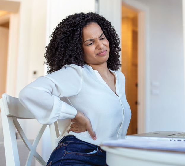 Woman holding low back while sitting in front of a laptop