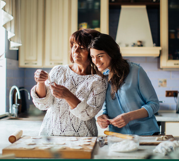 Older mother and adult daughter baking cookies together