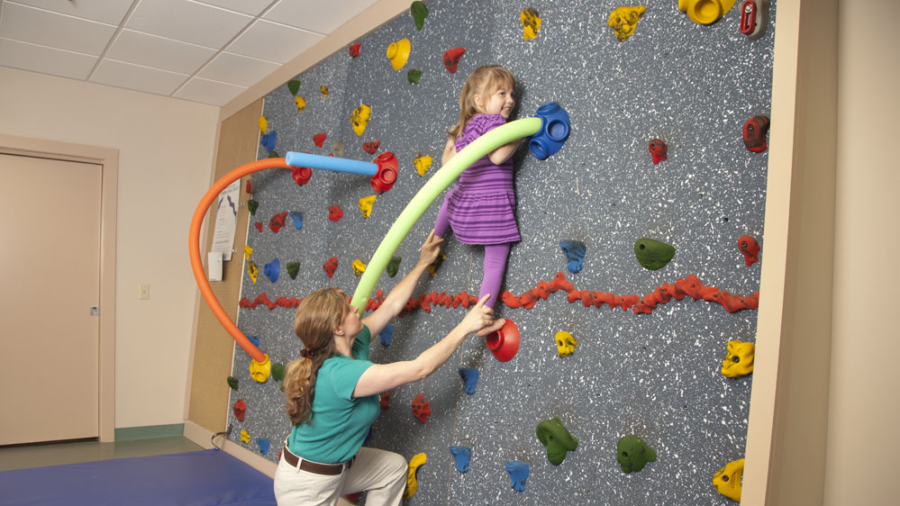 therapist spots a child on the climbing wall