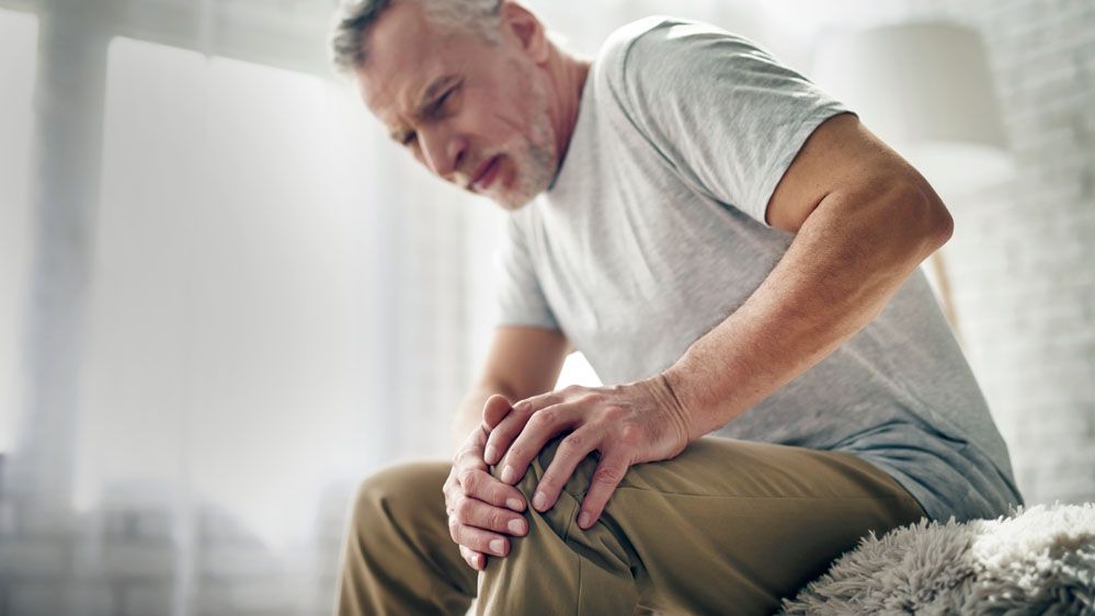 man holding his arthritic knee