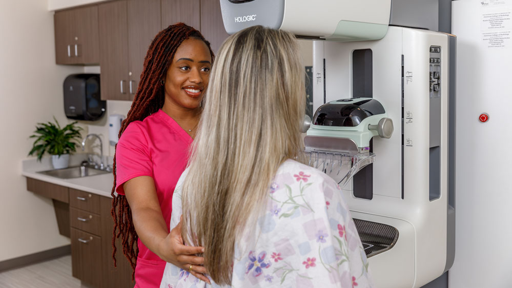 mammographer works with a patient