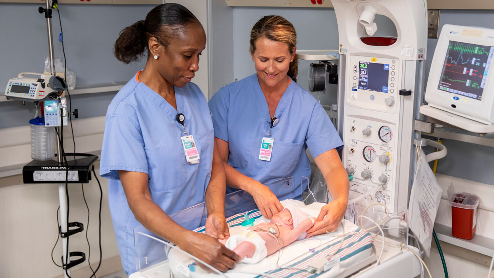 A CNA and RN care for a baby in the NICU